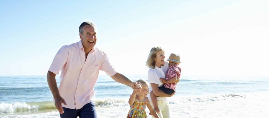 Family laughing and enjoying the beach on a sunny day.